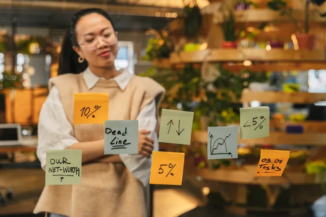 Woman analyzing sticky notes with graphs and deadlines in modern office space. How to build SAAS marketing buyer personas with evidence