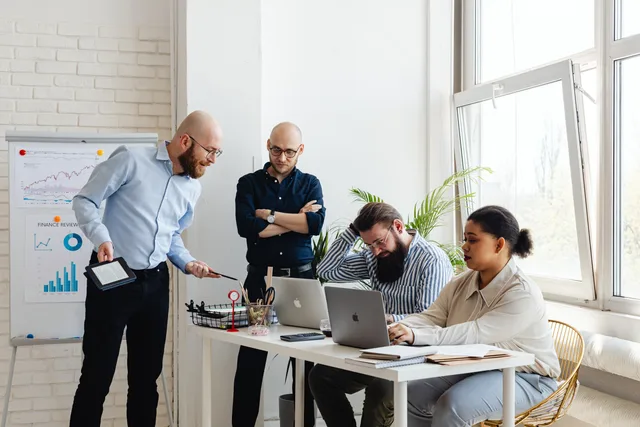 A diverse team discusses strategy in a modern office setting with laptops and charts. What a SAAS marketing channel strategy means for software teams