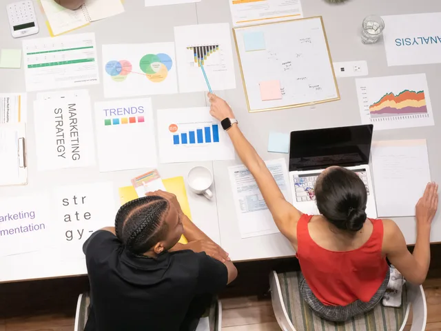 Colleagues collaborating on marketing strategy with documents and graphs in a modern office setting. What SAAS marketing commercial opportunities mean for British software firms