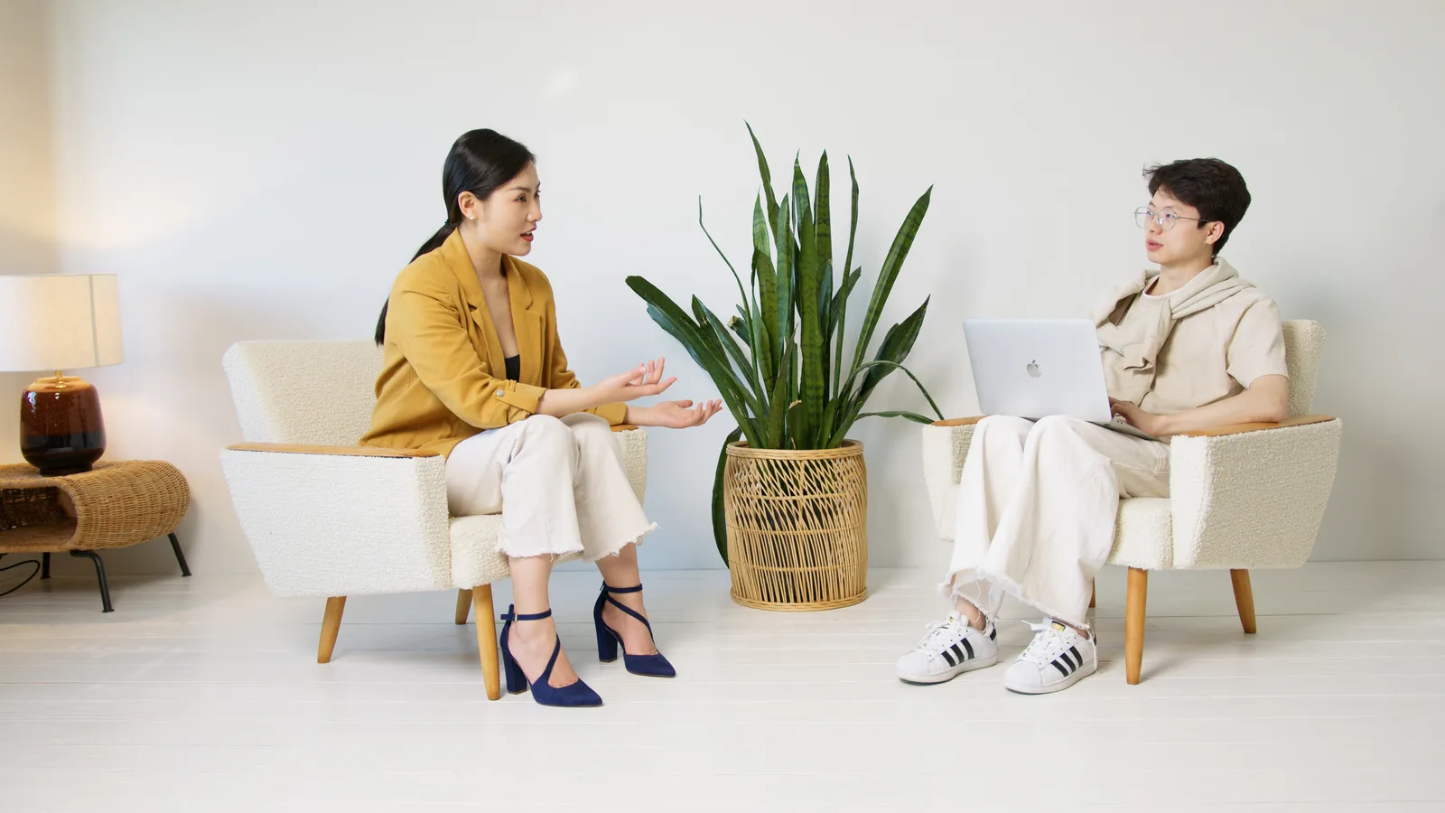 Two people having a casual interview session indoors with minimalist decor and a home plant.