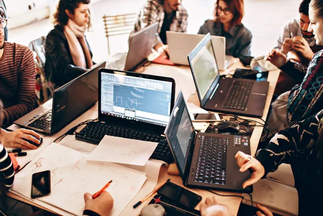 Group of diverse adults collaborating with laptops and papers in a modern office environment. What does SAAS marketing market size in England actually measure?